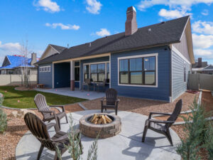 blue single family home with circular stone patio and firepit