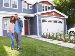 middle aged couple standing in front of blue house